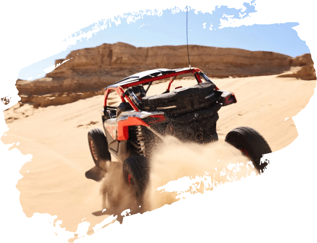 47c2a2d7c824681d3e1326e3c3a6d87fb6cbcbac Off-road vehicle driving on sandy terrain with rocky background.