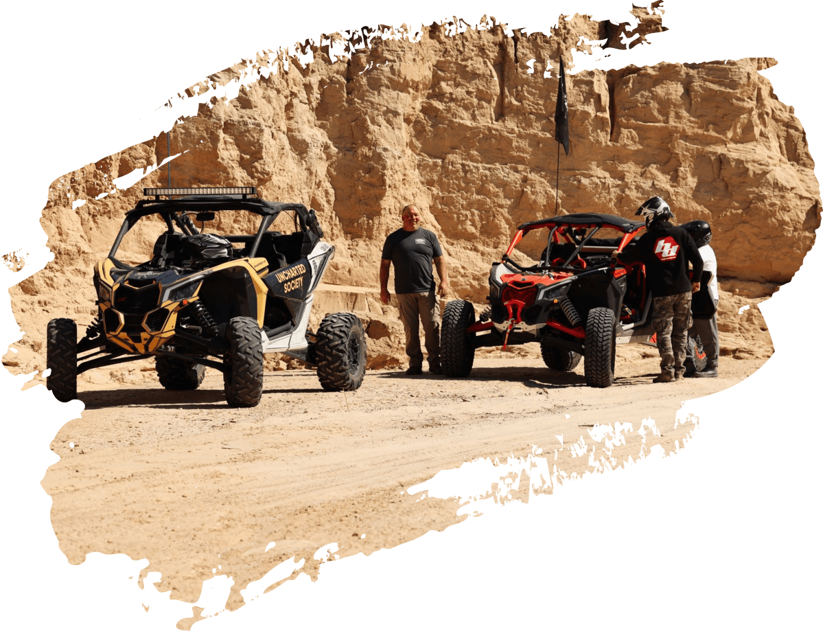 5af78d4e9952f6deee0bf611116f0e40708c31d8 Two off-road vehicles and three people on a desert dirt path.
