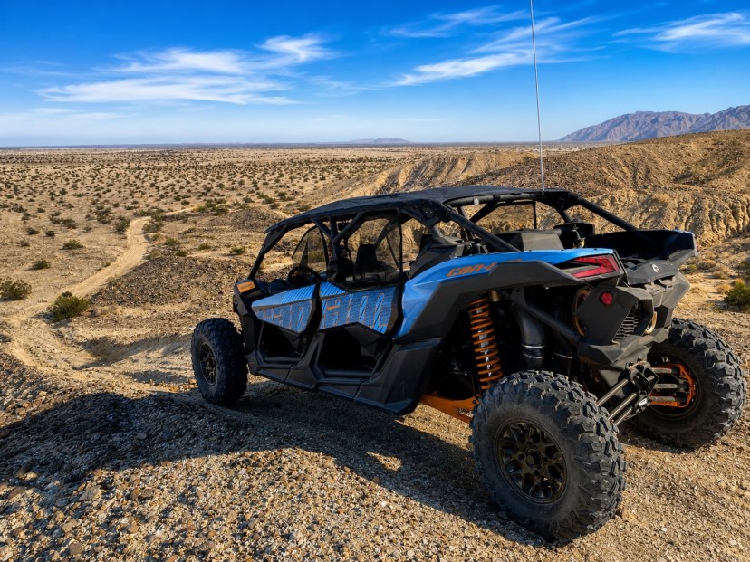 Off-road vehicle on rocky desert terrain under blue sky.